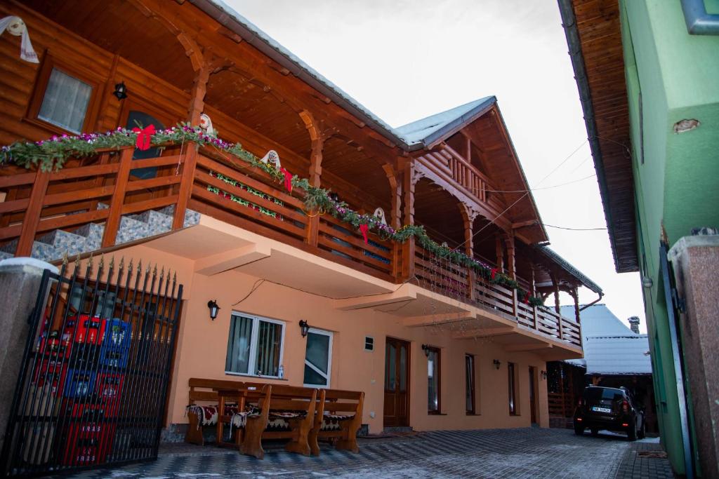 a building with a balcony and tables and chairs at Pensiunea Ioana Mariana in Botiza