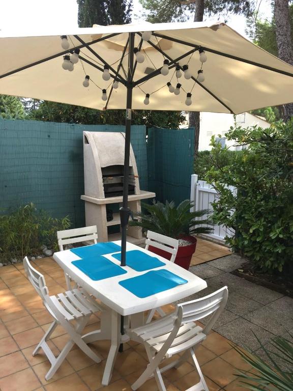 une table et des chaises avec un parasol sur une terrasse dans l'établissement 5100 Mas de la Pinède 210, au Cap d'Agde