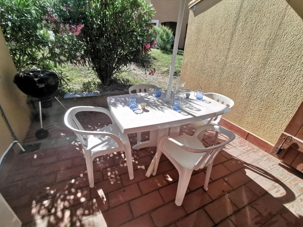 une table et des chaises blanches sur une terrasse en briques dans l'établissement 5004 Neptuna 66C, au Cap d'Agde