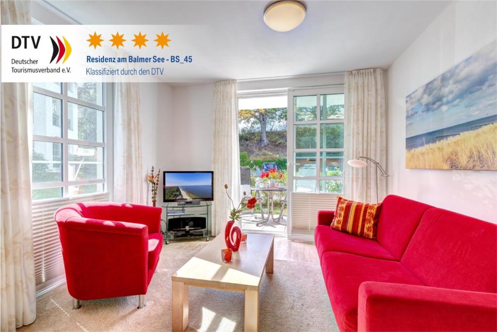 ein Wohnzimmer mit 2 roten Stühlen und einem TV in der Unterkunft Residenz am Balmer See - BS 45 mit Wellnessbereich in Balm