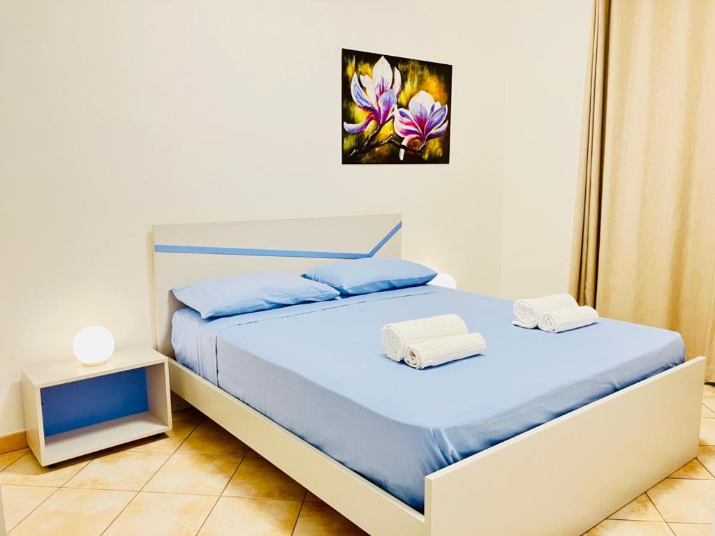 een slaapkamer met een bed met blauwe lakens en een schilderij aan de muur bij Holiday Apartment Nomina Castelsardo in Castelsardo