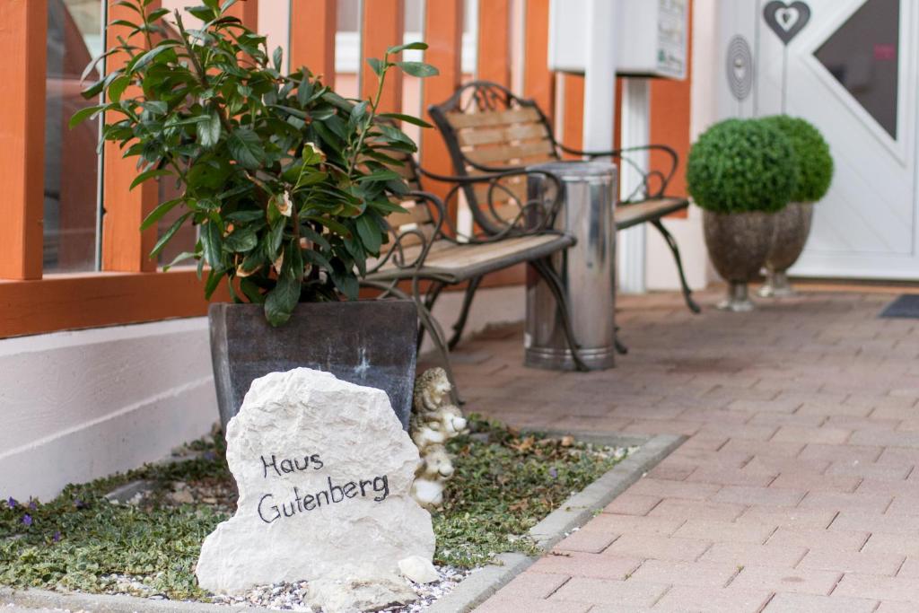 un cartel que dice que ahora jardinería sentado al lado de un banco en Hotel Garni Haus zum Gutenberg, en Hallbergmoos