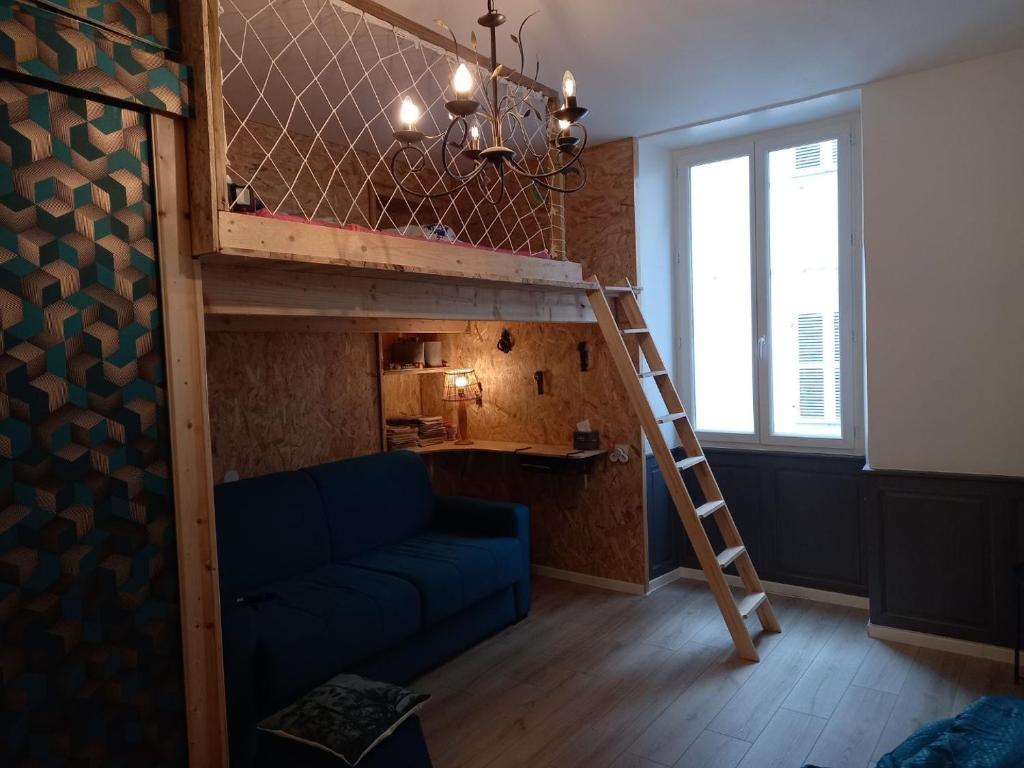 Una cama alta con un sofá azul en una habitación. en Appartement rue de la cascade 64440 Eaux-Bonnes, en Eaux-Bonnes