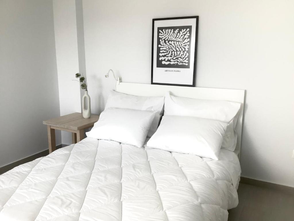 een bed met witte lakens en kussens in een slaapkamer bij Grand Panoramic Villa II Lagonissi in Lagonissi