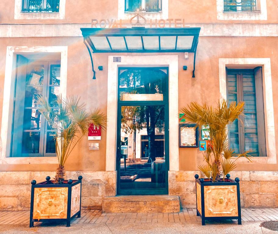 eine Tür zu einem Gebäude mit zwei Topfpflanzen draußen in der Unterkunft Royal Hôtel in Nîmes