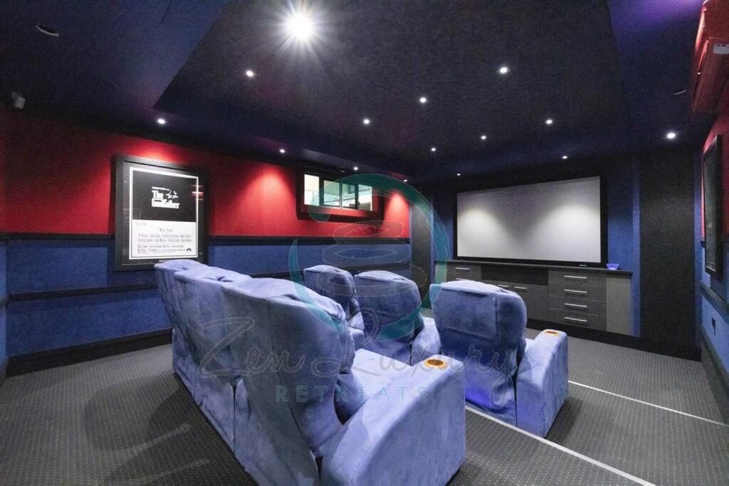 ZenLux: 4BR Bayview Mansion Infinity Pool + Cinema في Stuart Park: غرفة مسرح وكراسي زرقاء وتلفزيون بشاشة مسطحة