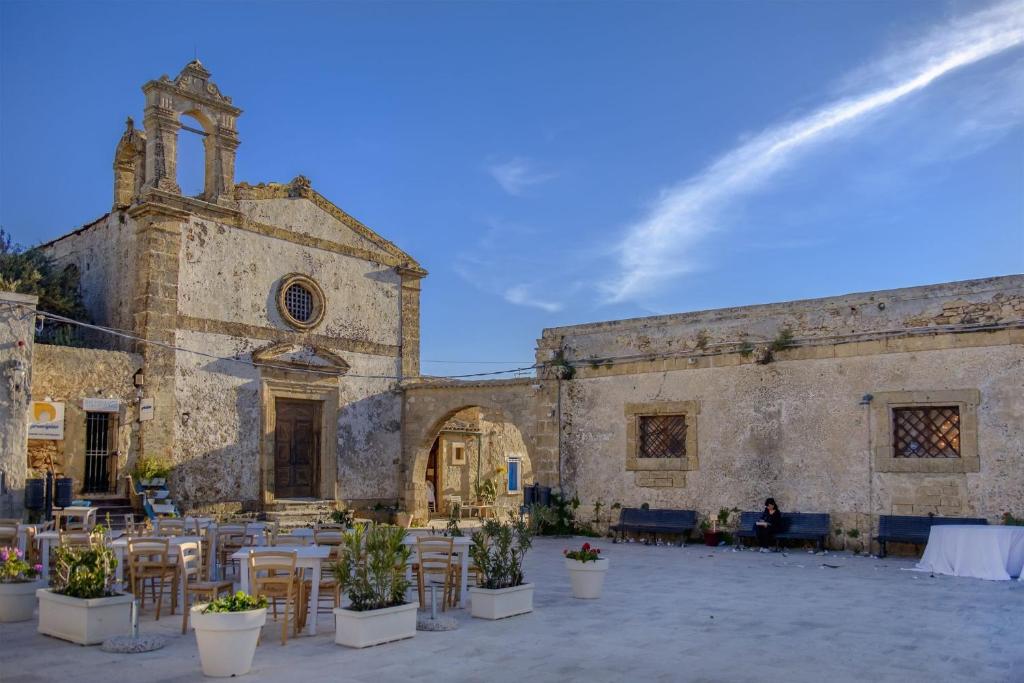 an old church with tables and chairs in front of it at La Perla a Marzamemi in Marzamemi