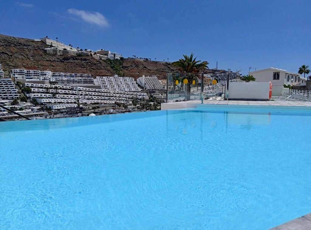 a large swimming pool with blue water in front of buildings at Apartamento Robi en Cumana II - Puerto Rico - Ap 508 in Puerto Rico de Gran Canaria