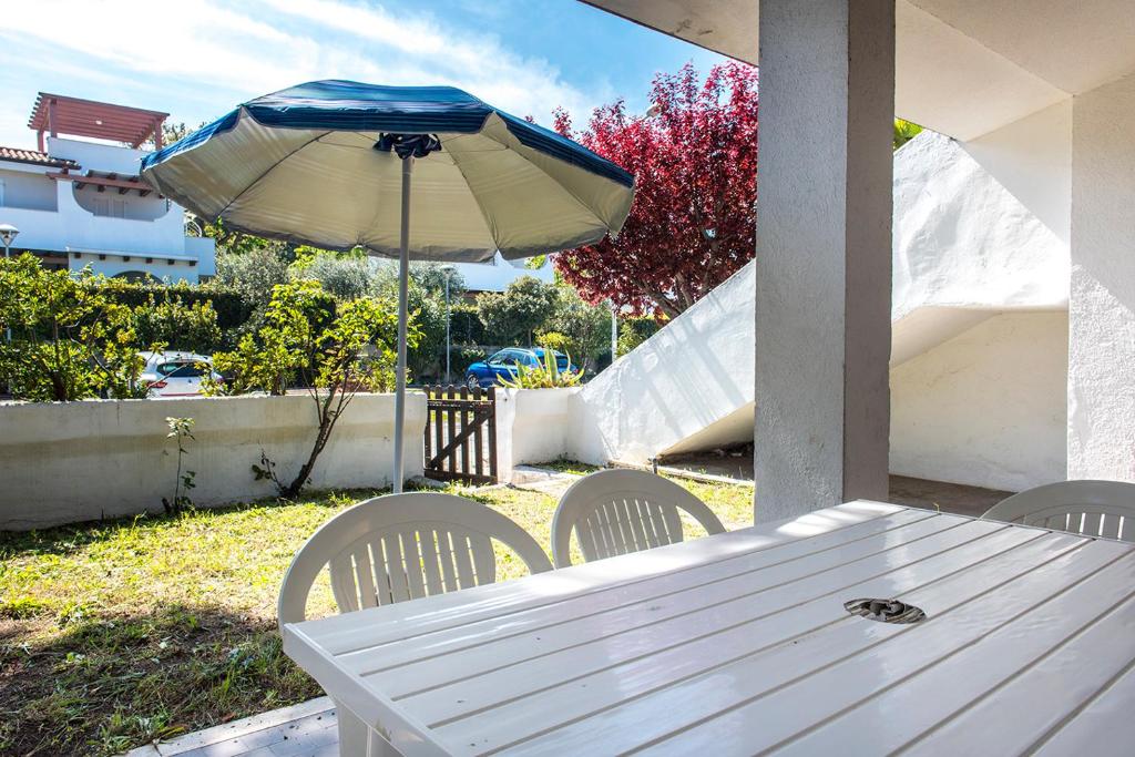 einen weißen Tisch und Stühle mit Sonnenschirm in der Unterkunft M049 - Marcelli, trilocale con giardino a 200 metri dal mare in Marcelli