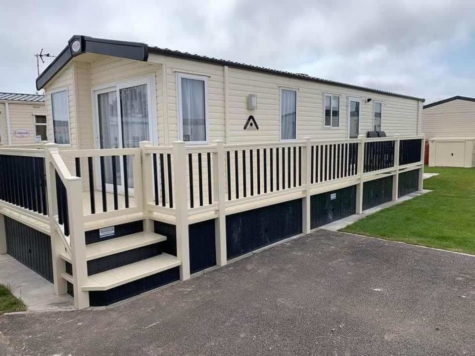 a house with a white fence and a porch at 6 BERTH DELUXE CARAVAN PALM GROVE 42 in Chapel Saint Leonards