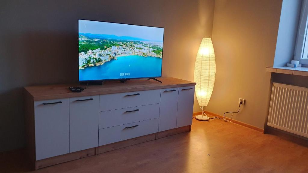 a living room with a flat screen tv on a cabinet at Apartament Ogrodzieniec in Ogrodzieniec