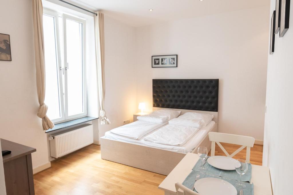 a white bedroom with a bed and a table at Charming Apartments Frankfurt City in Frankfurt