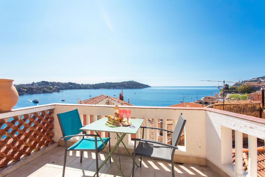 une table et des chaises sur un balcon avec vue sur l'océan dans l'établissement BELVEDERE AP1059 Villefranche-sur-Mer by Riviera Holiday Homes, à Villefranche-sur-Mer