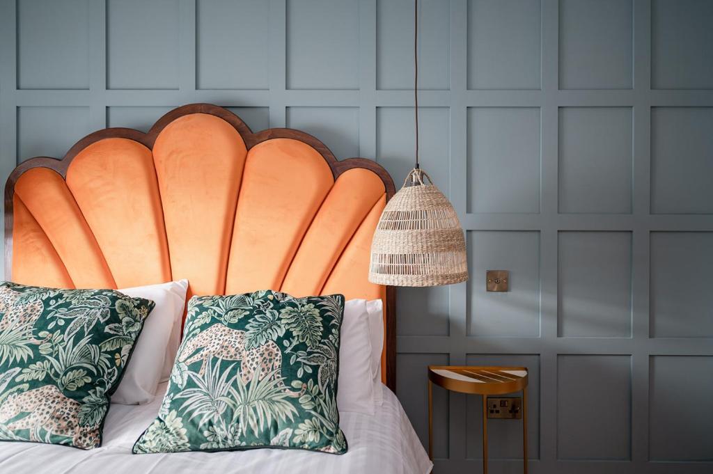 a bed with a large orange headboard with two pillows at The Seelies - Luxury Aparthotel - By The House of Danu in Kingussie