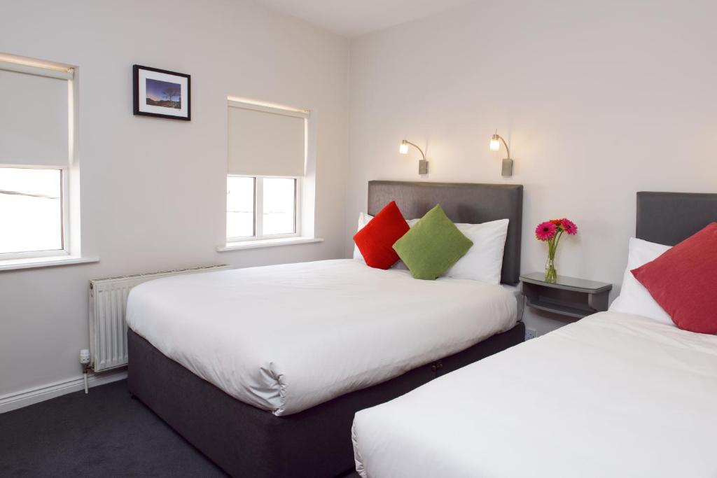 2 camas en una habitación con almohadas rojas y verdes en Dan Linehans Bar and B&B en Killarney