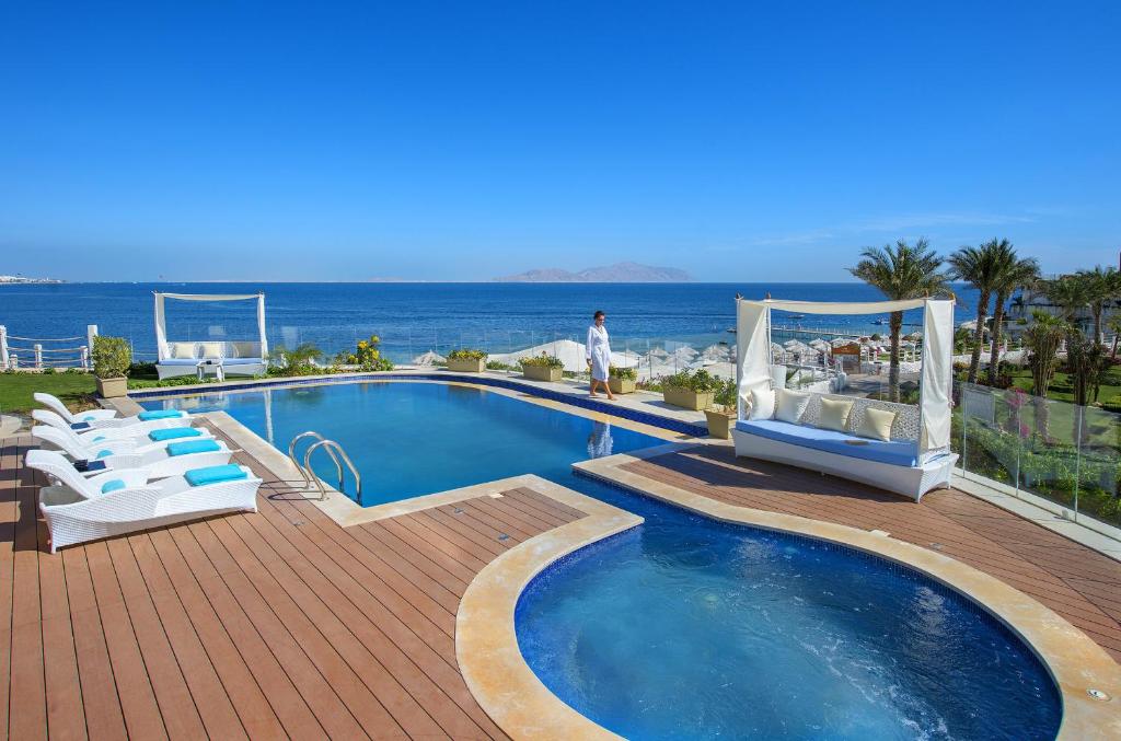 a swimming pool with chairs and the ocean in the background at Sunrise Arabian Beach Resort in Sharm El Sheikh