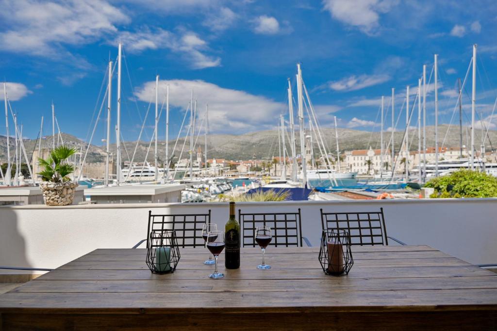 a wooden table with wine glasses on a balcony with boats at Apartman Ciciliani in Trogir