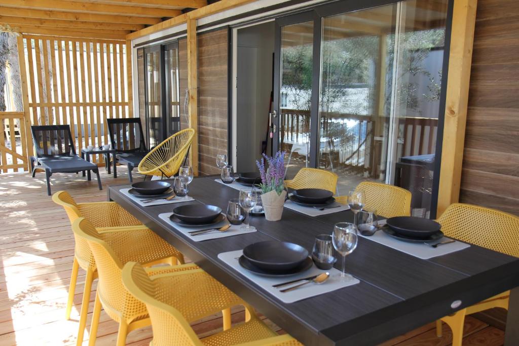 een zwarte tafel met gele stoelen en een tafel met glazen bij Mobile Home Bubamara in Drage