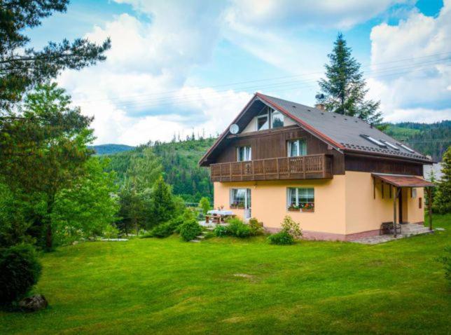 a large house in a field with a green yard at Chata u Tata in Mlynky 