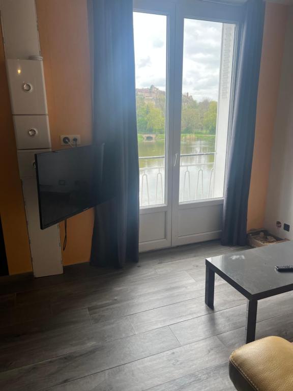 a living room with a television and a large window at Résidence bord de Loire euro 6 in Decize