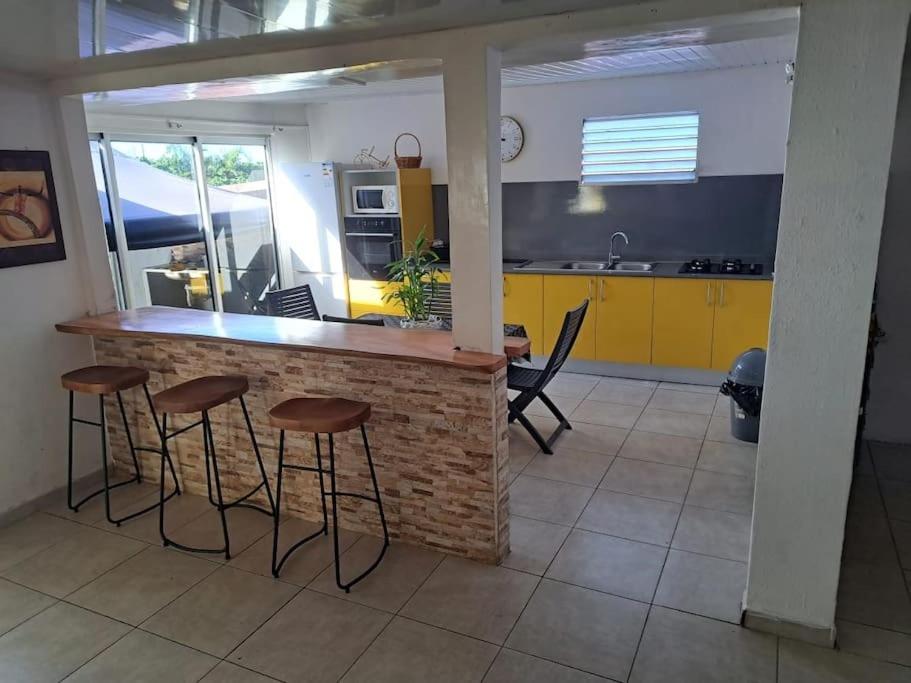 a kitchen with a bar with stools and a table at location Maison Basse-Terre GUADELOUPE in Basse-Terre