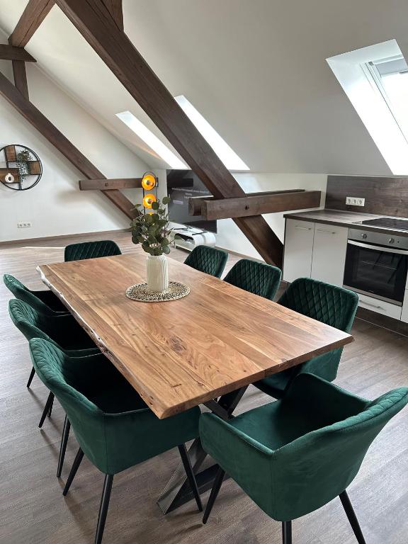a dining room with a wooden table and green chairs at Dachterrassenwohnung Katharinenschule in Eisenach
