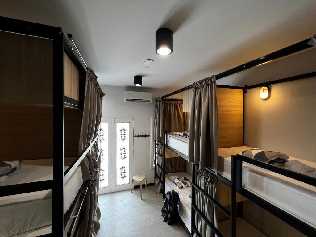 The Freedom Club Hostel KL في كوالالمبور: غرفة بها ثلاثة أسرة بطابقين وممر