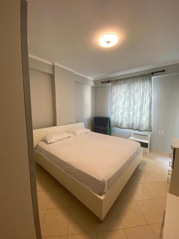 een slaapkamer met een wit bed en een raam bij Saranda relax apartments in Sarandë