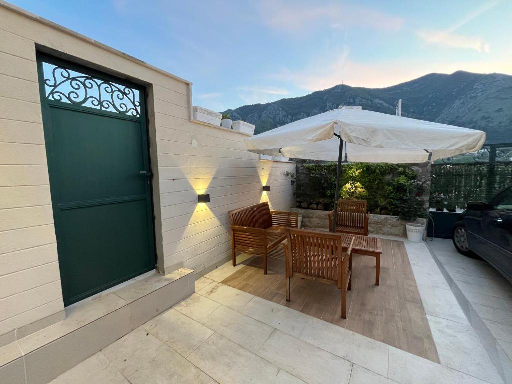 a patio with two chairs and a table with an umbrella at Villa Miramare , Dobrota seafront in Kotor
