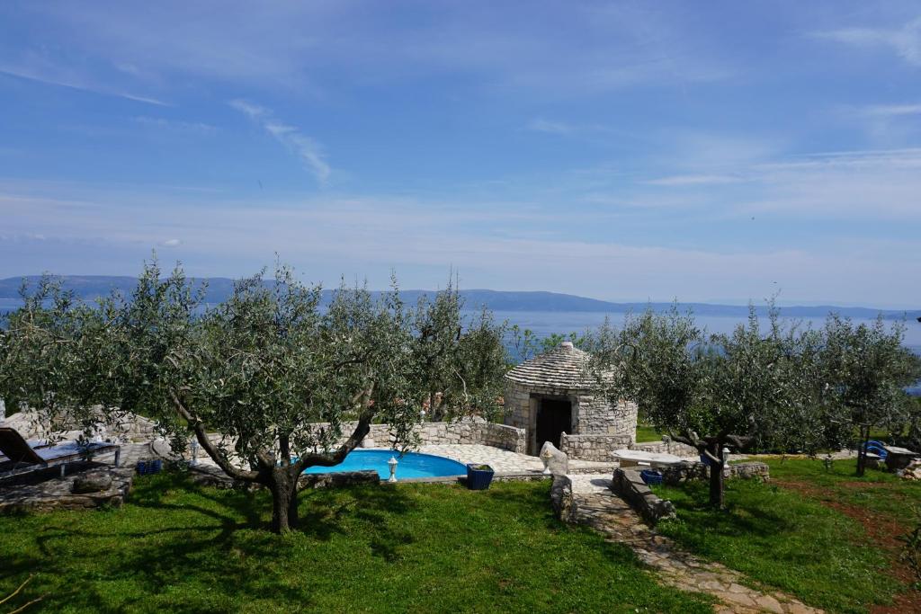a pool in a yard with trees and a building at Holiday Home Marino with Private pool and Sea View in Ravni