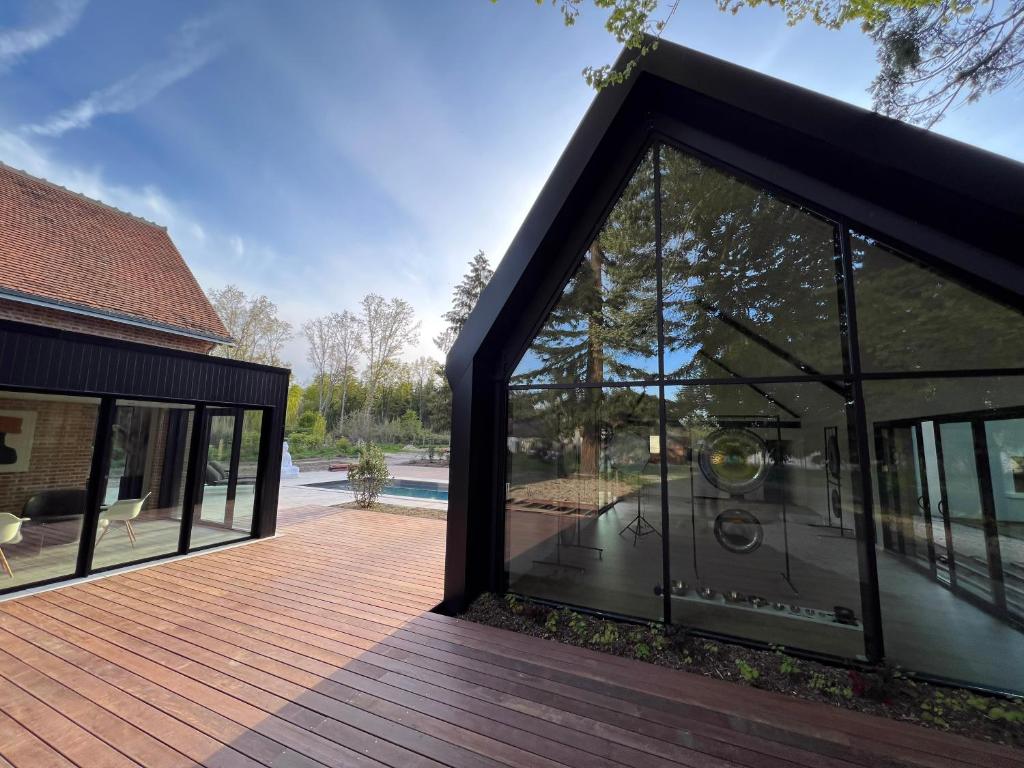 une extension en verre d'une maison avec une terrasse dans l'établissement Domaine Oranga, un design élégant au luxe épuré près des Châteaux de la Loire, à Lanthenay