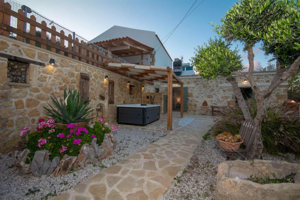 een stenen huis met een binnenplaats met bloemen bij Pamelas House with Jacuzzi in Kissamos