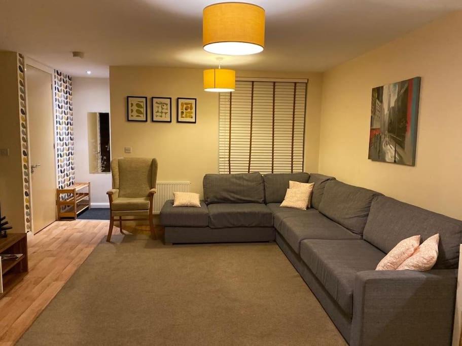a living room with a gray couch and a chair at Cosy House near city centre and football stadium in Manchester