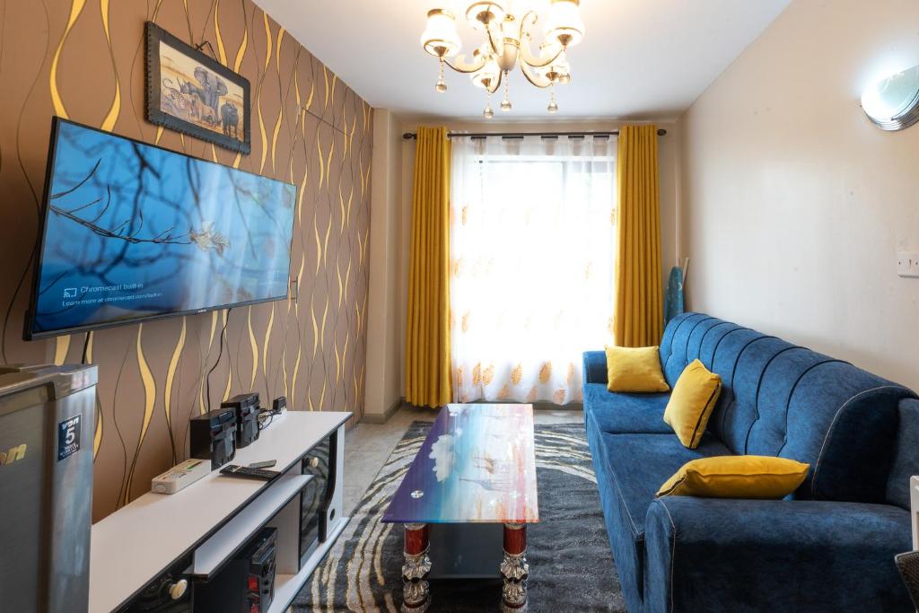 sala de estar con sofá azul y TV en The Bliss - Lovely 1 bedroom apartment located near TRM mall en Nairobi