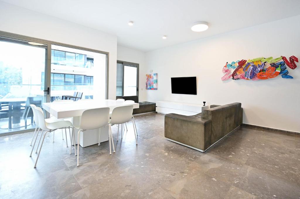 a dining room with a white table and a tv at Mamma Mia by HolyGuest in Tel Aviv