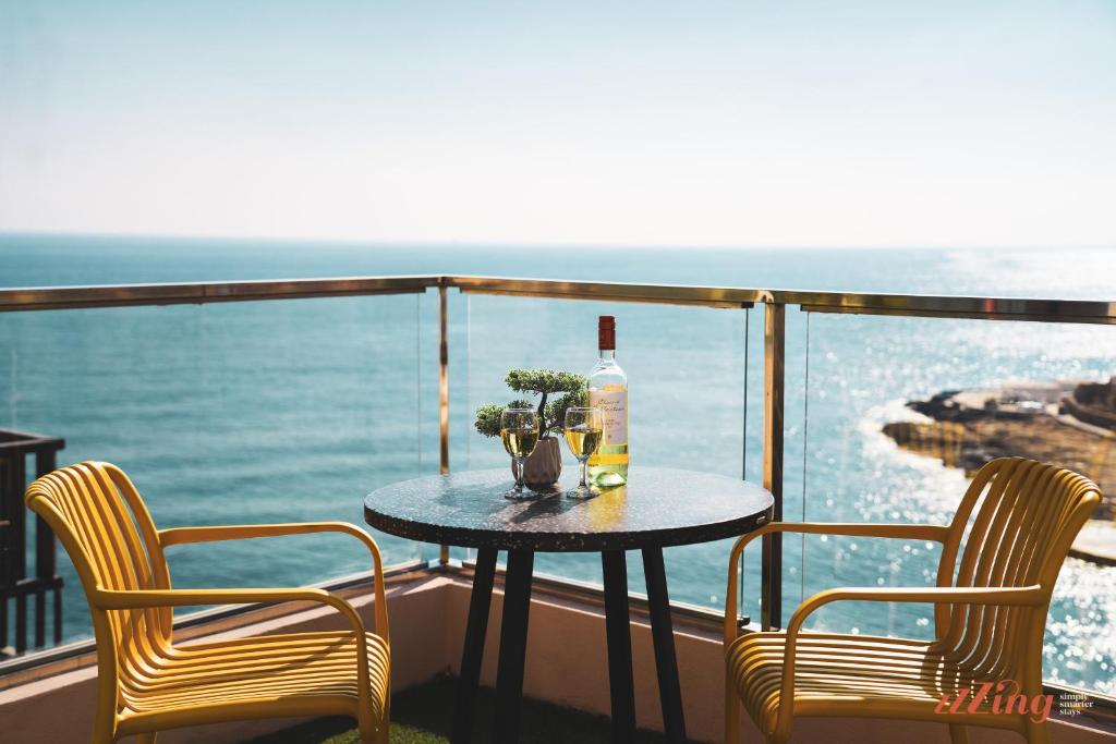 a table with a bottle of wine and two chairs on a balcony at Gorgeous seaviews from a stunning studio in Sliema