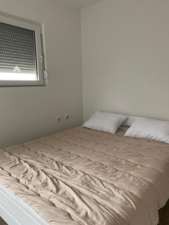 uma cama num quarto branco com uma janela em Apartman Milena Temerin em Temerin