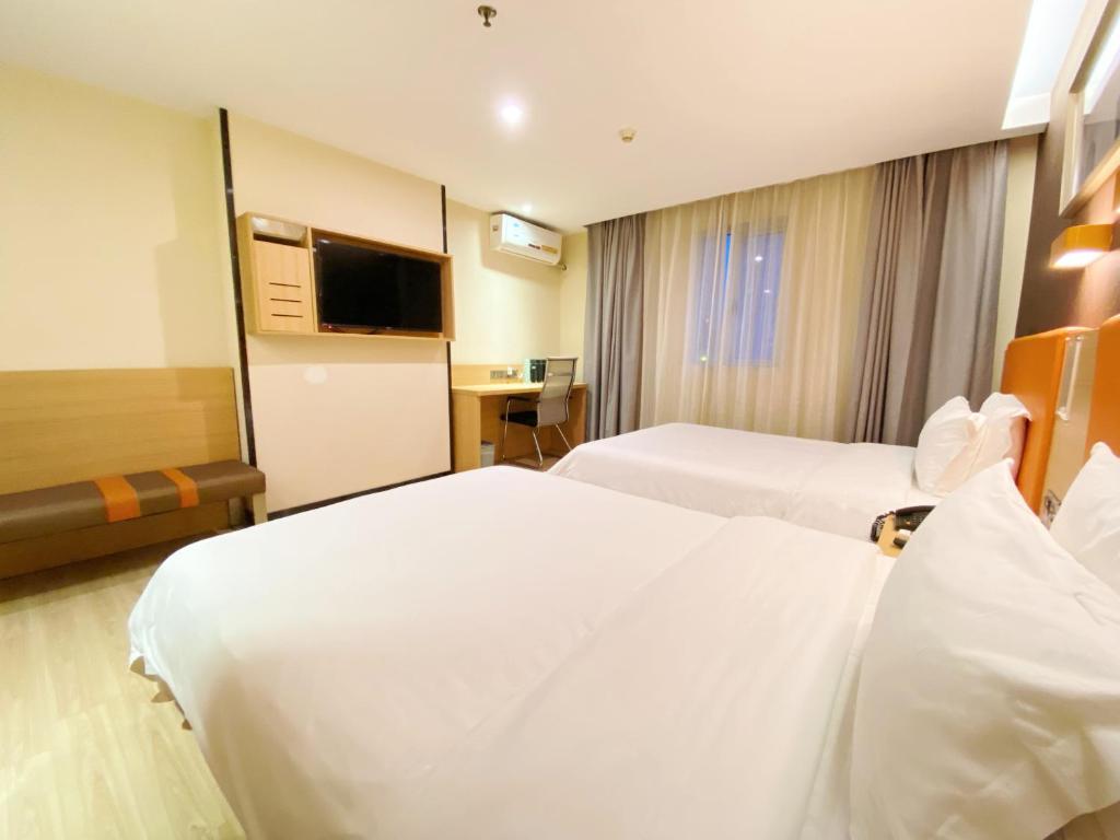 a hotel room with two beds and a television at 7Days Premium Guangzhou Chenjiaci Dukang Avenue in Guangzhou