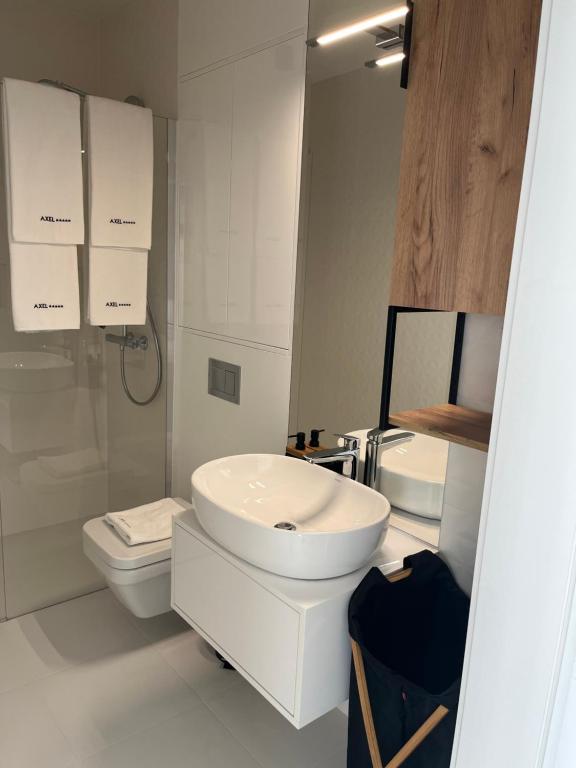 Baño blanco con lavabo y aseo en AXEL WAVE Seaview Apartment &SPA, en Międzyzdroje