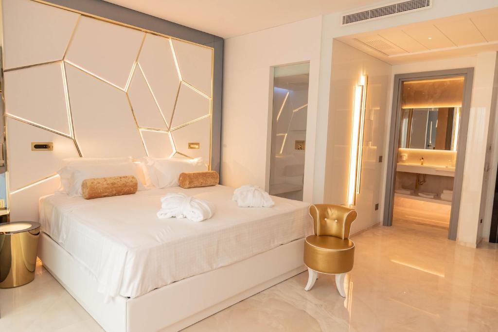 1 dormitorio con 1 cama blanca y 1 silla de oro en The Promenade Luxury Wellness Hotel, en Riccione