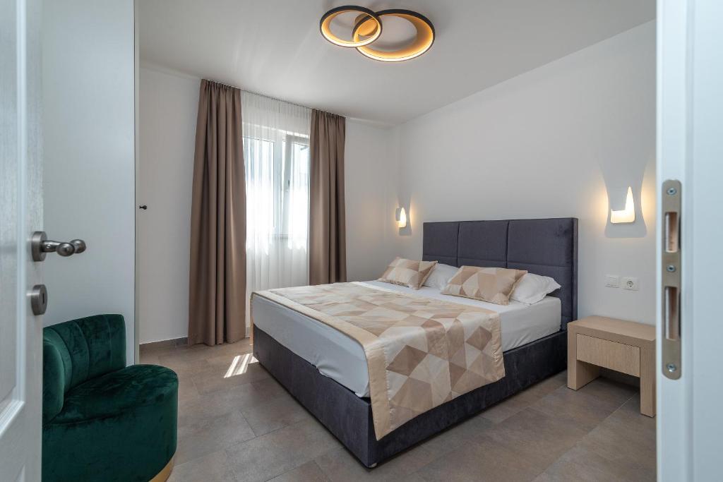 een slaapkamer met een bed en een groene stoel bij Apartments Liam in Trogir
