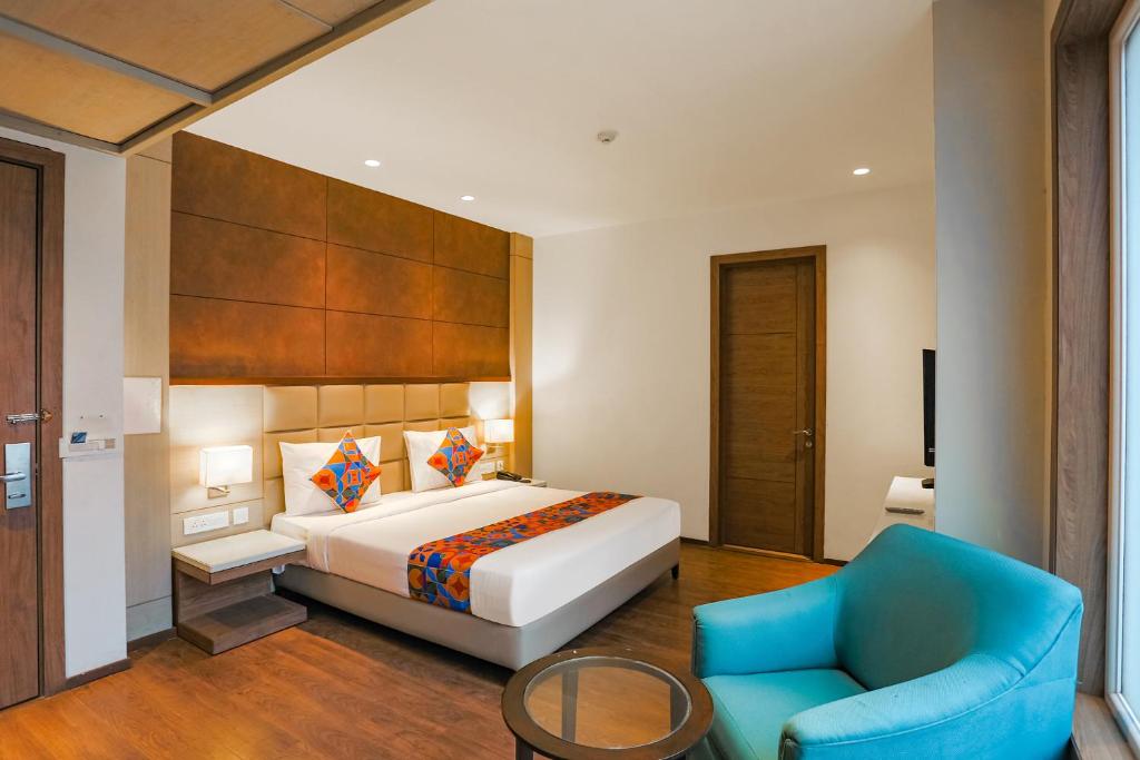 a hotel room with a bed and a blue chair at FabHotel Hexa Chhatarpur in New Delhi