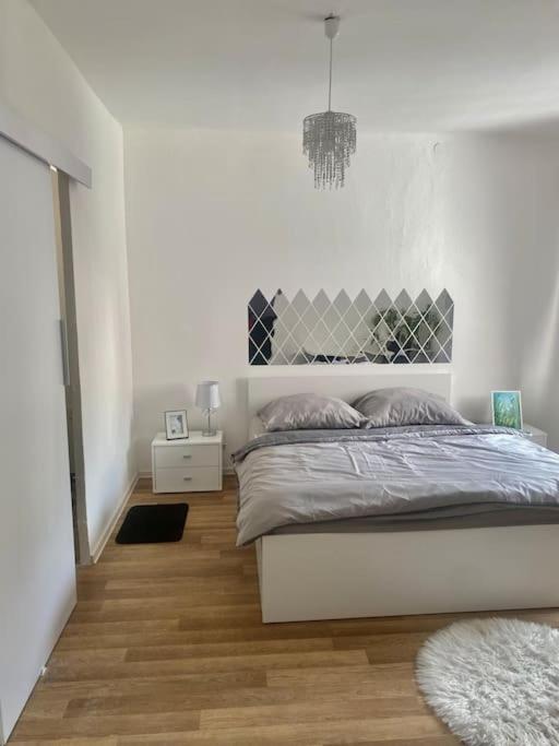 a white bedroom with a bed and a wooden floor at Zuzanittin rozpravkový domček in Rožňava