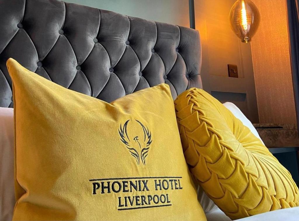 a yellow pillow on a bed with a black headboard at The Phoenix Collection in Liverpool