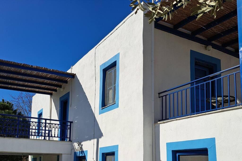 ein weißes Gebäude mit blauen Fenstern und einem Balkon in der Unterkunft LA-REEF at Lakki, Leros in Lakkíon