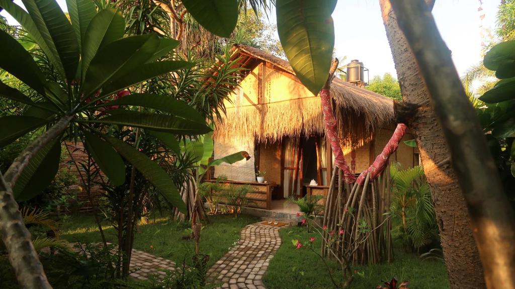 a house with a thatched roof with a path in front at UTOPIA in Gili Air