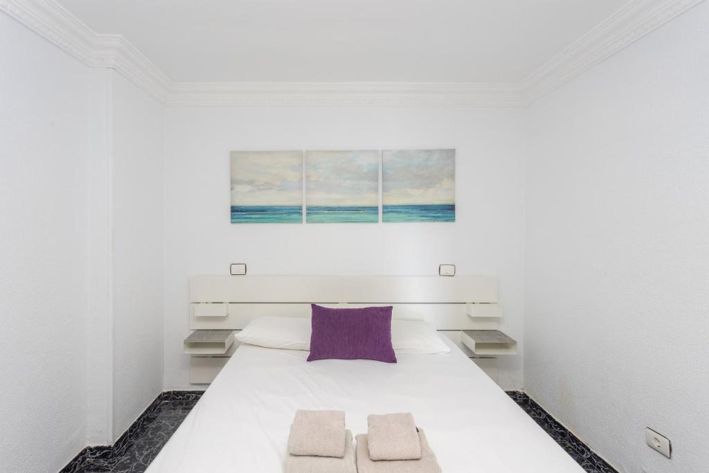 sypialnia z białym łóżkiem i fioletową poduszką w obiekcie Lightbooking playa de Amadores La Concha w mieście Puerto Rico de Gran Canaria