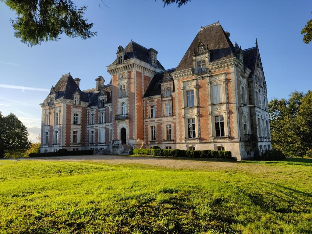 Saint-EstèpheにあるChambres d'hôtes au château de Puycharnaudの草原を前に置いた古城
