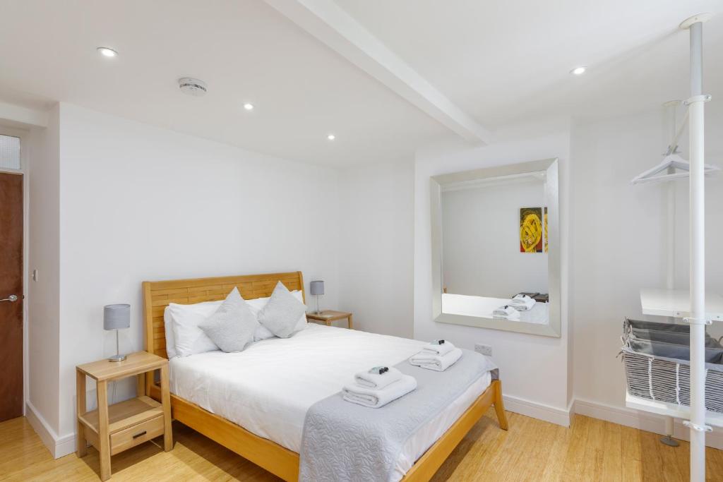 a white bedroom with a bed and a mirror at Spacious central Hove 1-bed flat in Brighton & Hove