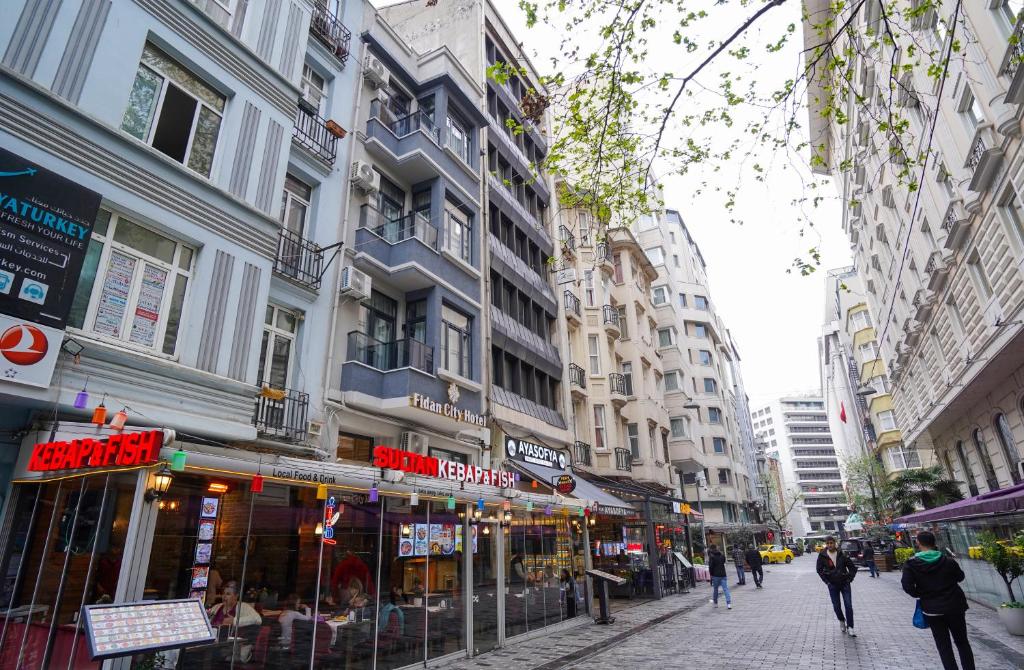 une rue de ville avec des bâtiments et des gens marchant dans la rue dans l'établissement Fidan City Hotel, à Istanbul